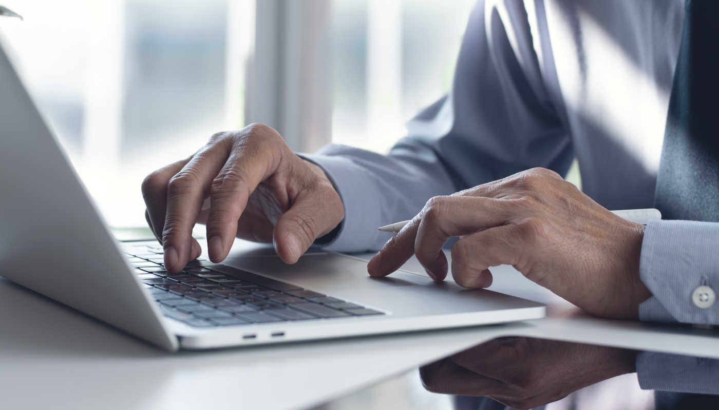 Scenery: A notebook on a desk. On it the hands of a man in a business look.