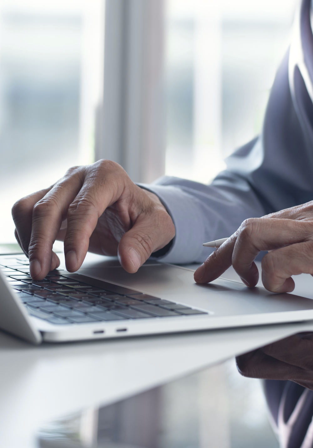 Scenery: A notebook on a desk. On it the hands of a man in a business look.