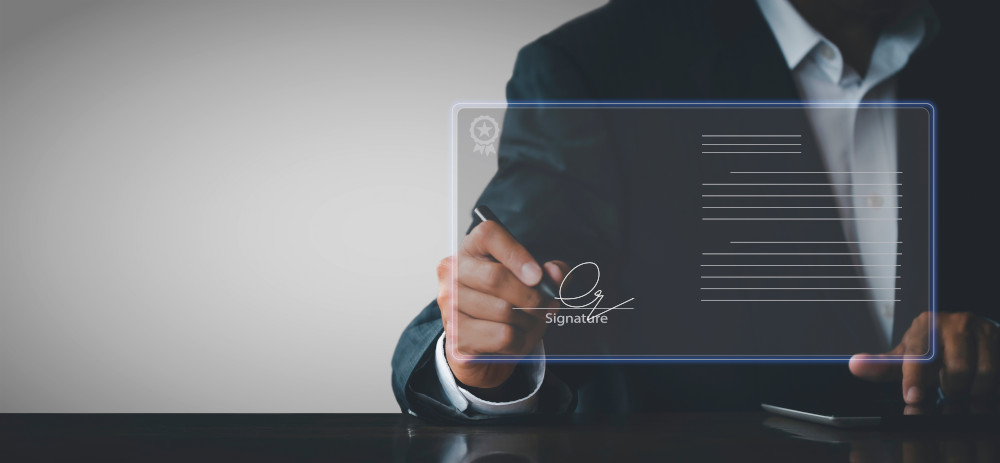 Montage: „A symbolically represented digital document in the foreground of the picture is signed by a businessman with a pen“
