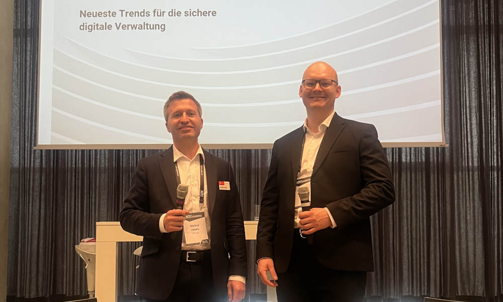 Szenerie: Markus Vesely und Konstantin Wollinger lächeln vor ihrer Präsentation in die Kamera.