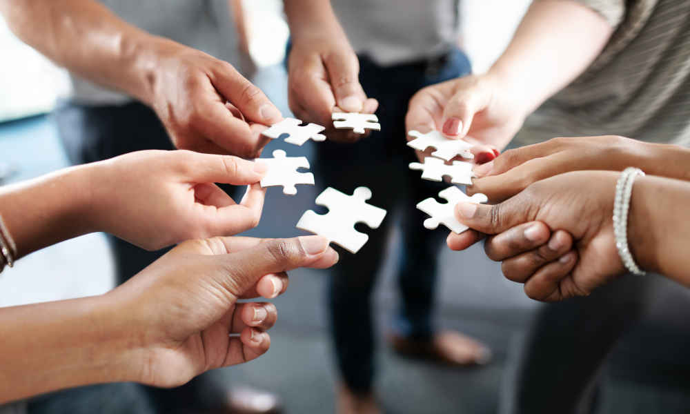 Hände, die Puzzelteile in der Mitte zusammenfügen